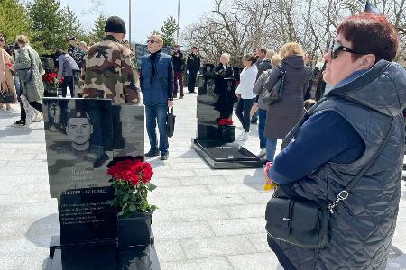 　ウクライナ侵攻で戦死した息子ニキータ・リャミンさんの墓の前に立つ母マリーナさん（右端）＝２５日、ロシア・ウラジオストク（共同）