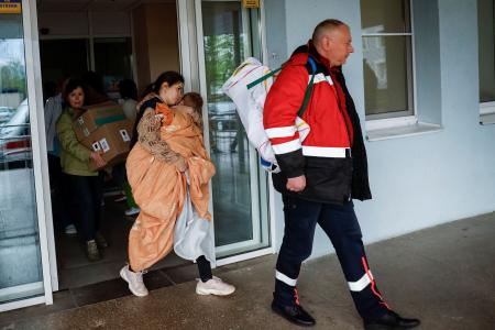 　２６日、ウクライナ・キーウの病院から避難するする子どもを抱えた女性（右から２人目）（ロイター＝共同）