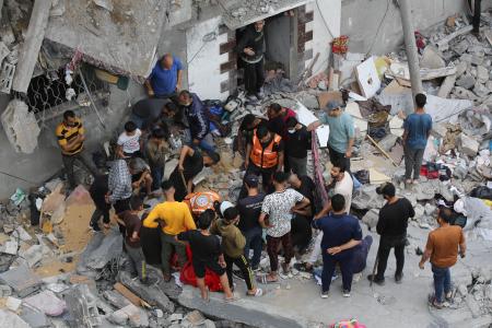 　２７日、ガザ地区中部デールバラハへのイスラエル軍の攻撃後、破壊された建物付近で救助に当たる人々（ゲッティ＝共同）