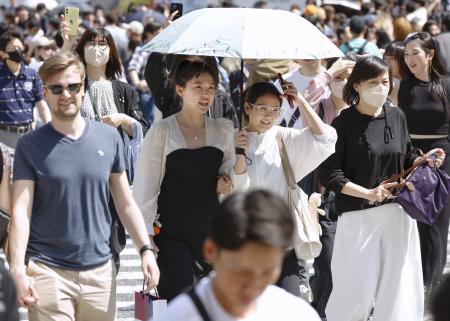　東京・渋谷のスクランブル交差点を日傘を差して歩く人たち＝２８日午後