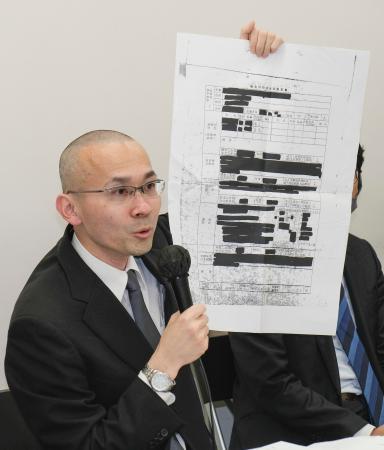 　判決後の記者会見で、滋賀県側が開示した大半が黒塗りの文書を示す京都新聞の森敏之記者＝９日午後、大阪市