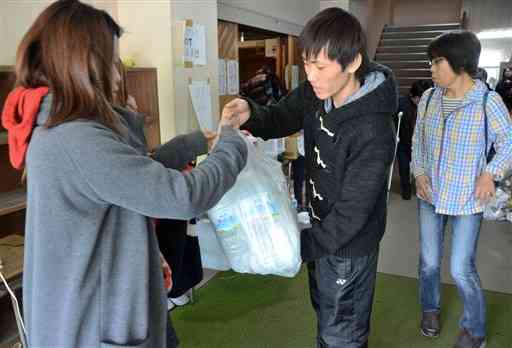 会員制交流サイトを通じて熊本北高に集まった支援物資を配るボランティア＝２０１６年４月１８日、熊本市北区