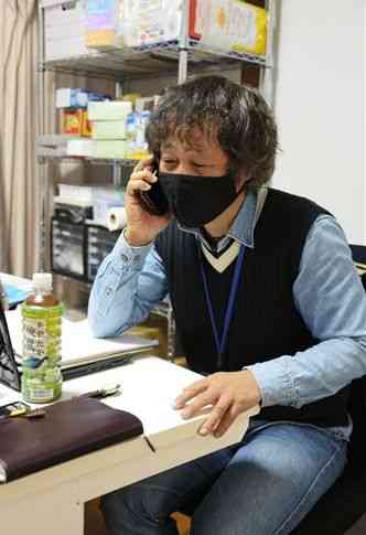 支援している生活困窮者と電話で話す高木聡史さん。ＳＯＳの電話は休日や夜間を問わずかかってくるという＝１８日、熊本市東区