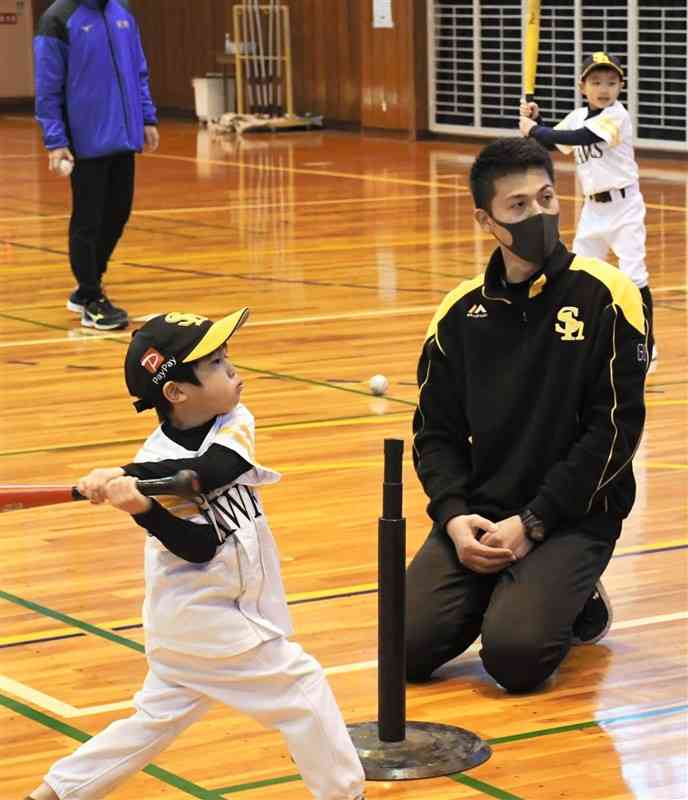 ティー打撃でフルスイングする子どもたち。右は東方伸友コーチ＝2月、熊本市西区の県立総合体育館