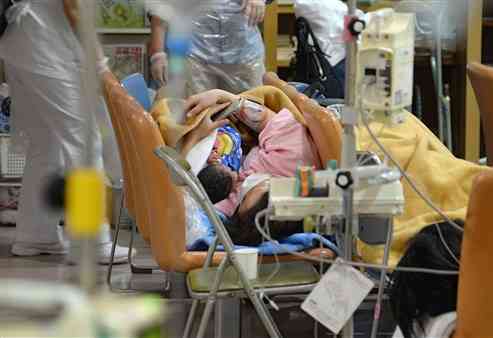 熊本市民病院の１階に避難し、生まれたばかりの乳児を抱く女性＝４月１６日午前４時５分ごろ、熊本市東区（横井誠）