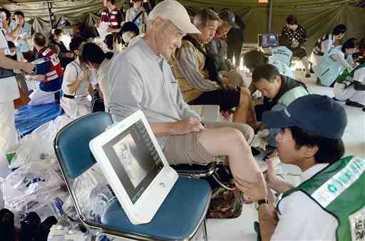 避難者らの足にエコーを当て、血栓ができていないかどうか調べるプロジェクトチーム＝４月２９日、益城町のグランメッセ熊本