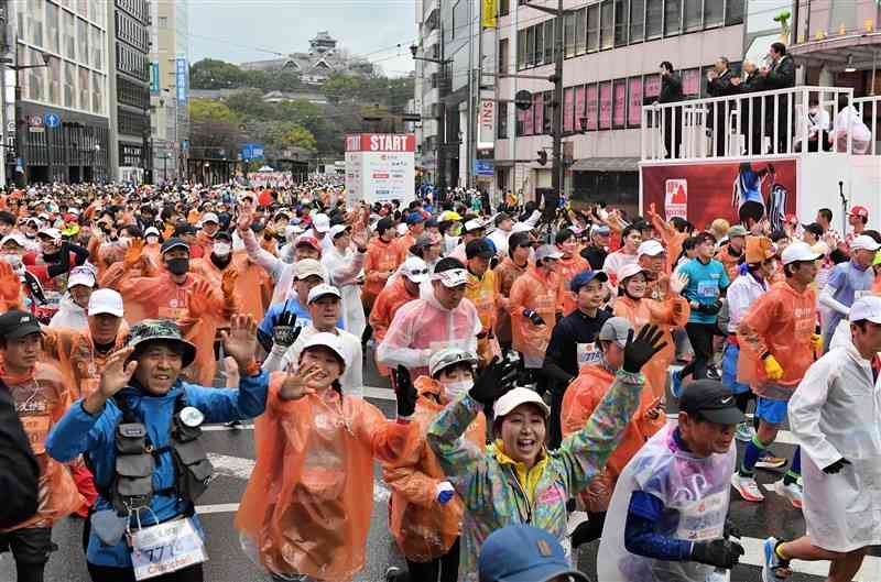 熊本城をバックにスタートするフルマラソンのランナー＝19日午前、熊本市中央区の通町筋電停前