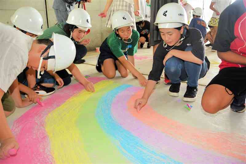 本妙寺トンネル内の舗装前のコンクリートに虹の絵を描く児童たち＝熊本市西区