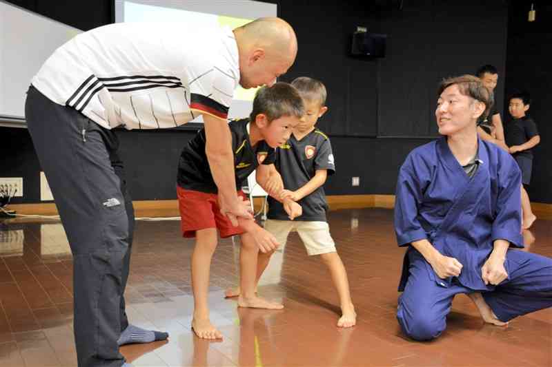 松村健之さん（右）から古武術の体の使い方を学ぶ親子＝熊本市西区