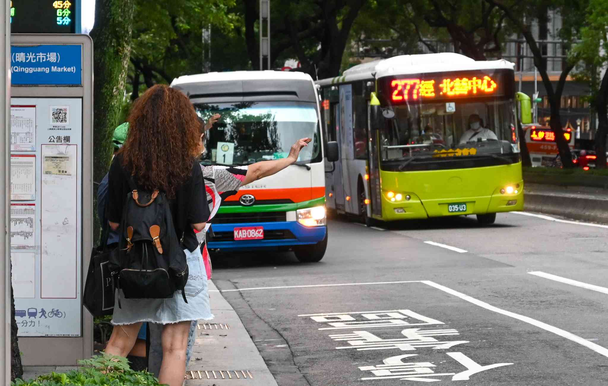 ▲乗車するため、走行するバスに向かって手を挙げる人たち＝９月４日、台北（ＮＮＡ撮影）
