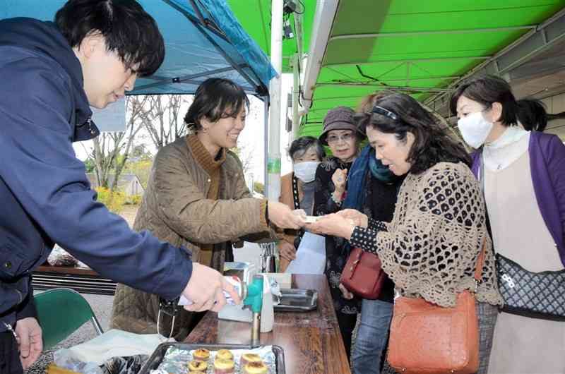 カフェの店主ら（左）から、カライモのスイーツを受け取る買い物客ら＝11日、大津町