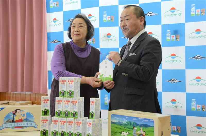 県酪連が贈った牛乳1万9200本の目録を受け取ったフードバンク熊本の鬼塚静波代表（左）＝21日、熊本市南区