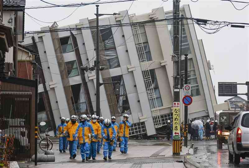 3日、石川県輪島市で救出や捜索の活動にあたる警察官ら。奥は倒れたビル