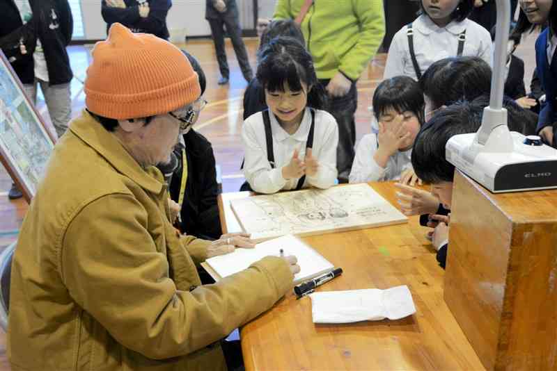湯出小の児童に囲まれながらイラストを描く江口寿史さん＝17日、水俣市