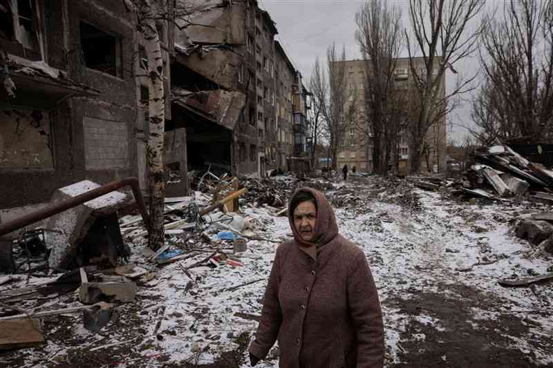 ロシアのミサイルこうげきでこわされた集合住宅（じゅうたく）の横を歩く女性（じょせい）＝2月、ウクライナ東部（ロイター＝共同）