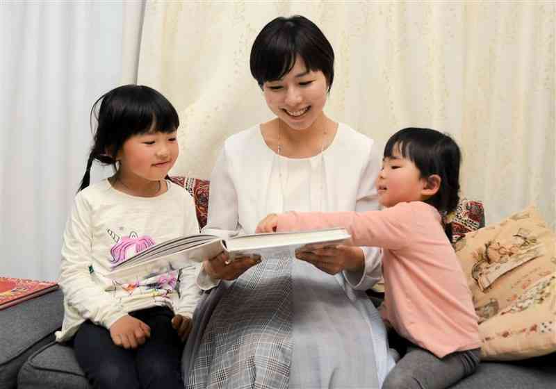 自宅で2人の娘に絵本を読み聞かせる山置有希さん（中央）＝5日、熊本市中央区
