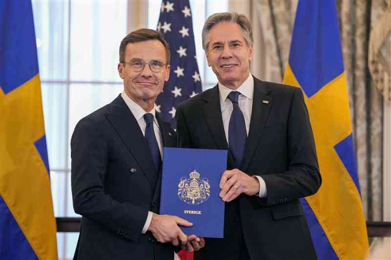 スウェーデンの首相（左）とアメリカの国務（こくむ）長官。手にしているのは、スウェーデンが（A）のメンバーになったことを記した文書＝7日、アメリカのワシントン（AP＝共同）