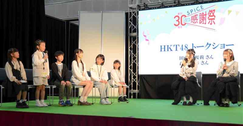「くまにち　すぱいす」の創刊30周年感謝祭で開かれたHKT48トークショーで、メンバーの2人（右側）に質問するくまTOMOサポーター＝3月23日、益城町