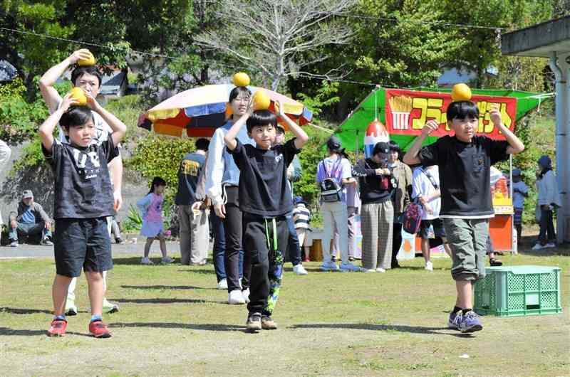 浅海ばんかん祭りで、河内晩柑を頭に乗せて歩くゲームに挑戦する参加者＝14日、天草市