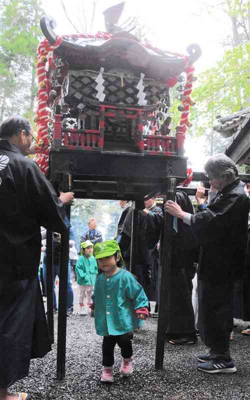 乙姫神社の春の例大祭で無病息災を願ってみこしの下をくぐる園児ら＝15日、阿蘇市