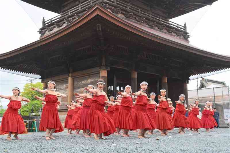 阿蘇神社の楼門を背に古典フラを披露する「美しい阿蘇山古典フラ伝承会」のメンバー＝27日、阿蘇市