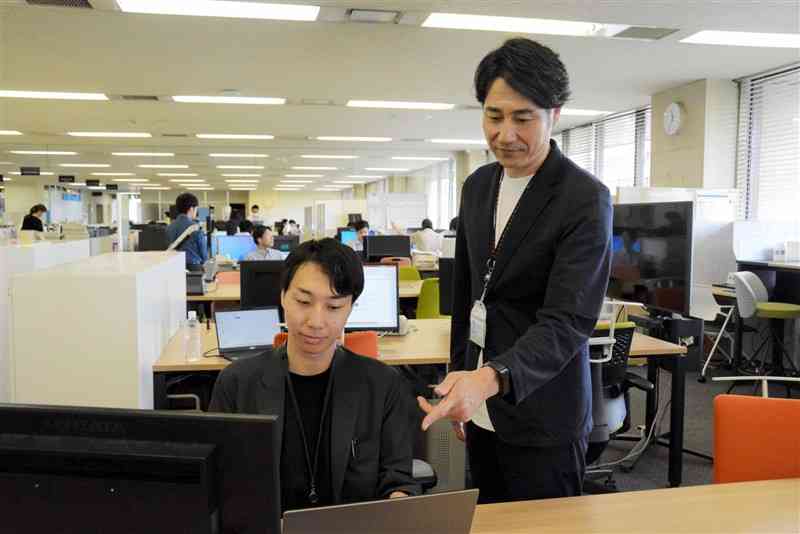 Tシャツにジャケット姿で勤務する熊本市改革プロジェクト推進課の職員＝1日、市役所