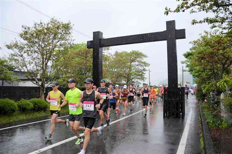 関所に見立てた冠木門をくぐってスタートする関所健康マラソンの参加者＝4月29日、南関町