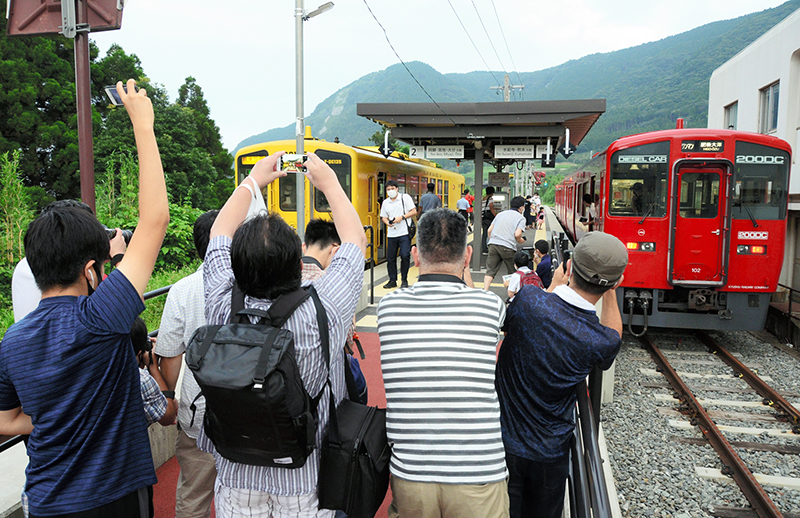 ＪＲ立野駅に並んだ上りと下り始発列車を撮影する鉄道ファン＝2020年８月８日午前、南阿蘇村
