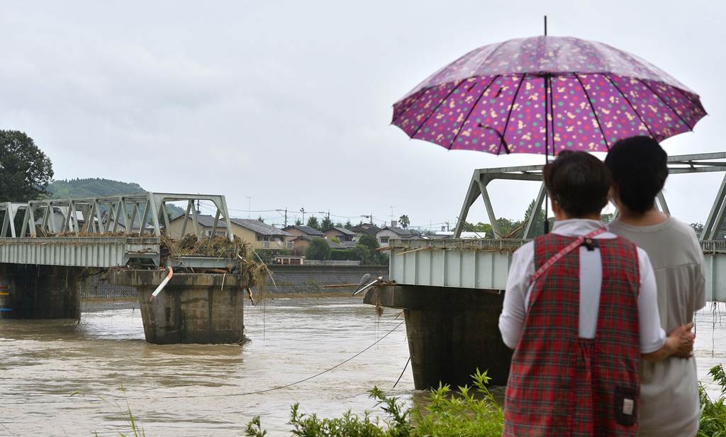 豪雨で中央部分が流された西瀬橋を見つめる近く住民＝５日午前１０時半すぎ、人吉市（高見伸）