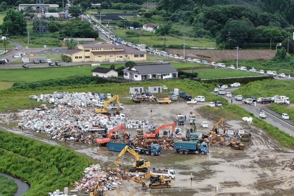 次々と持ち込まれる災害ごみ置き場。国道２２１号（上）は渋滞が発生している＝９日午後２時２５分ごろ、人吉市上漆田町（池田祐介、小型無人機で撮影）