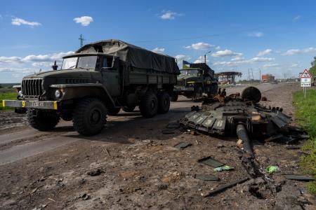 　１３日、ウクライナ・ハリコフ北部で、ロシア軍戦車の残骸のそばを通り過ぎるウクライナ軍車両（ＡＰ＝共同）