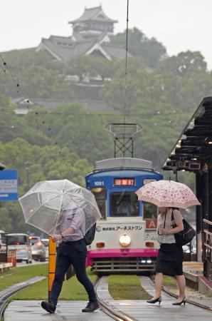 　傘を差して熊本市内を歩く人たち。上は熊本城＝５日午前８時１１分