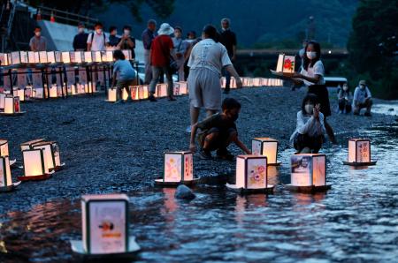 　日航ジャンボ機墜落事故から３７年を控え、「御巣鷹の尾根」の麓を流れる神流川に灯籠を流す人たち＝１１日夕、群馬県上野村