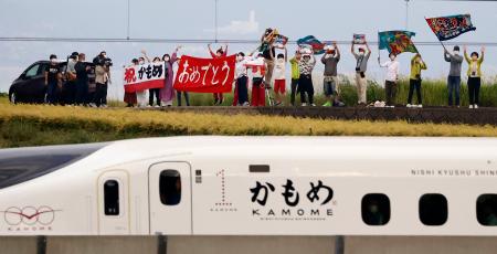 　旗や横断幕を手に、西九州新幹線開業を歓迎する人たち＝２３日午前７時１２分、長崎県大村市