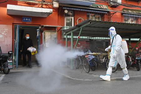 　新型コロナ対策で住宅街を消毒する作業員＝２５日、北京（共同）