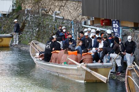 　保津川下りの舟が転覆した現場付近から、京都・嵐山の下船場所に運ばれた人たち＝２８日午後３時３３分