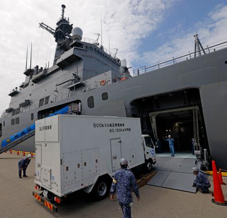 　海上自衛隊の大型輸送艦「しもきた」に積み込まれる九州電力送配電の発電機車＝２６日午前、福岡市の博多港