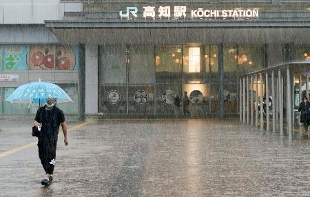 　ＪＲ高知駅前で、強い雨の中を歩く人＝２日午前８時７分