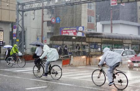 　強い雨の中、自転車で横断歩道を渡る人たち＝２日午前７時５３分、高知市