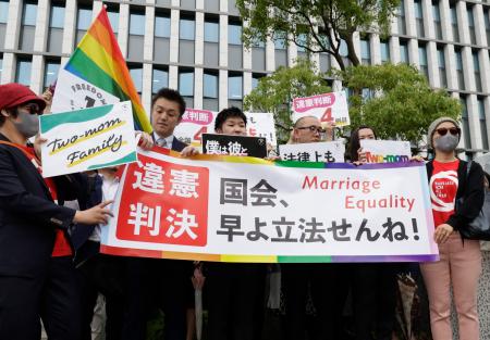 　同性婚を巡る福岡地裁判決を受け横断幕を掲げる原告ら＝８日午前、福岡地裁前