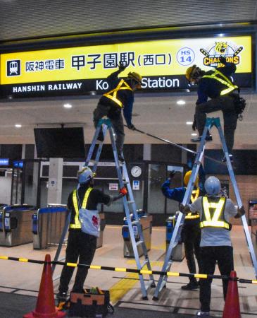 　終電後、黒と黄色の優勝記念版に付け替えられる阪神電鉄甲子園駅の駅名看板＝１５日未明、兵庫県西宮市