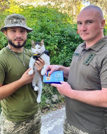 　ウクライナ軍に貢献したとして賞を授けられたネコと、飼い主のオレクサンドル・リャシュクさん（左）＝９月、ウクライナ南部（リャシュクさん提供・共同）