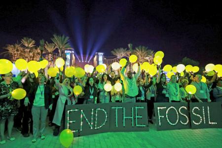 　ＣＯＰ２８の会場で、化石燃料の廃止に合意するよう求める環境団体メンバーら＝１１日、アラブ首長国連邦のドバイ（ロイター＝共同）