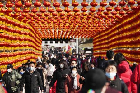 　春節を迎え、ちょうちんが飾られた道を歩く人たち＝１月、北京（共同）