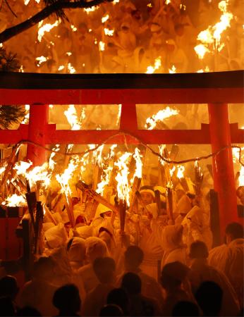 　神倉神社の伝統の火祭り「お灯まつり」で、燃えさかるたいまつを手にする白装束の男衆＝６日夜、和歌山県新宮市