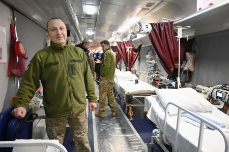 　ウクライナ国鉄が公開した「医療列車」の説明をする軍医（左）＝１４日、キーウ（共同）