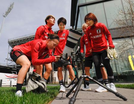 　８日、米オハイオ州コロンバスのスタジアム脇で、日食を撮影しているカメラのモニターをのぞき込むサッカー女子日本代表の選手ら（共同）