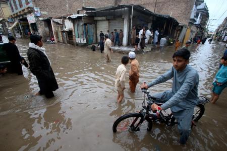 　パキスタン北西部ペシャワルで冠水した道路を歩く人々＝１５日（ＡＰ＝共同）