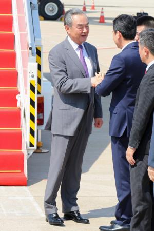 　２１日、カンボジア・プノンペンの空港で関係者と握手を交わす中国の王毅外相（共同）