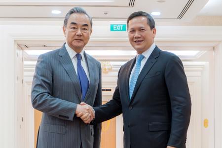 　中国の王毅外相（左）と握手するカンボジアのフン・マネット首相＝２２日、プノンペン（クメール通信提供、ＡＰ＝共同）